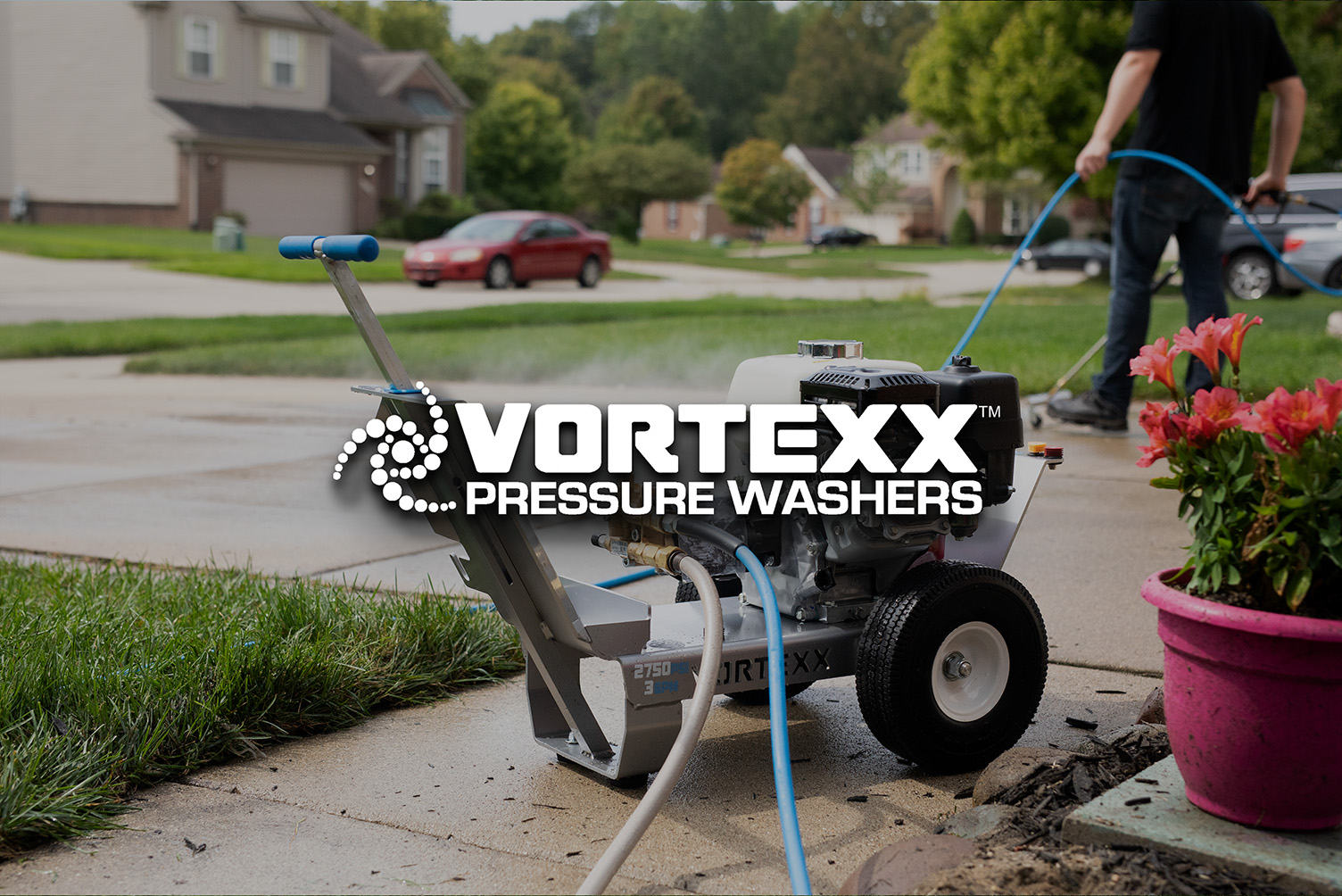 A Vortexx pressure washer in use on a driveway with a garden hose ...